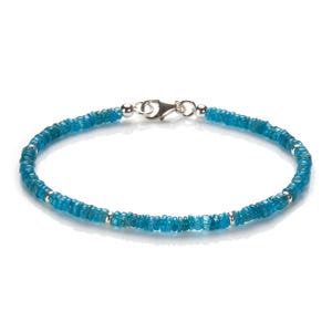 Peut inclure: Un bracelet en pierres bleues avec un fermoir argenté. Le bracelet est composé de petites perles rondes.