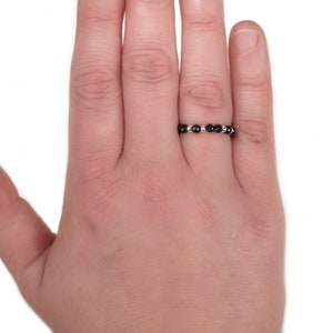 May include: A silver ring with black beads.