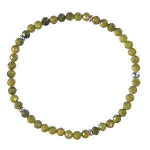 Op de afbeelding: Een armband van groene edelstenen met zilveren kralen. De armband is gemaakt van kleine, ronde kralen die aan elkaar geregen zijn op een zilveren ketting.