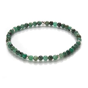 Puede incluir: Un brazalete de cuentas de piedras preciosas verdes con detalles plateados. El brazalete está hecho de pequeñas cuentas redondas y está enhebrado en una fina cadena plateada.