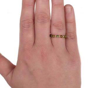 May include: A gold ring with a band of small, faceted green gemstones.