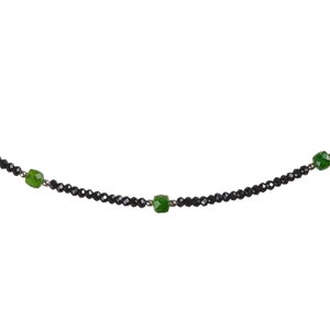 May include: A black beaded necklace with three green gemstone accents.