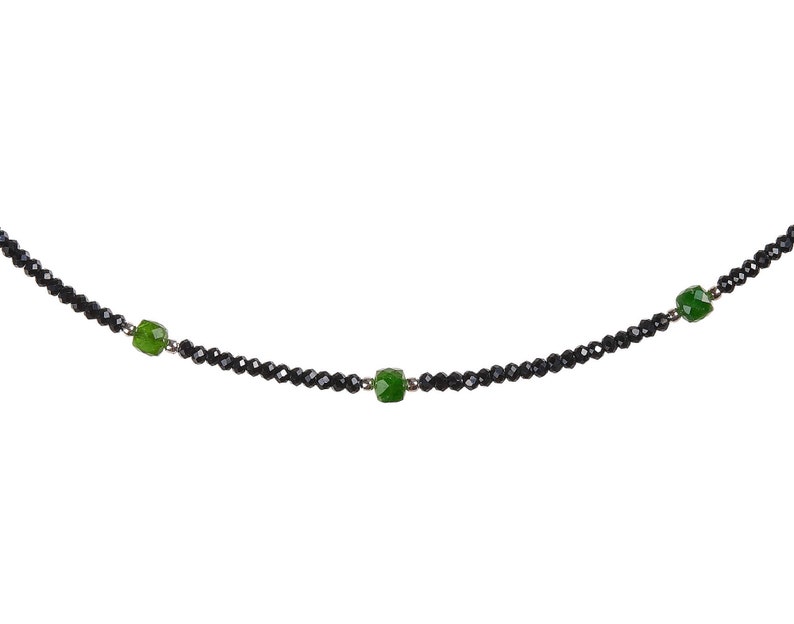 May include: A black beaded necklace with three green gemstone accents.
