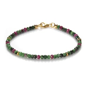 Könnte beinhalten: Ein goldenes Armband mit grünen und rosafarbenen Edelsteinen. Das Armband besteht aus kleinen, runden Perlen.