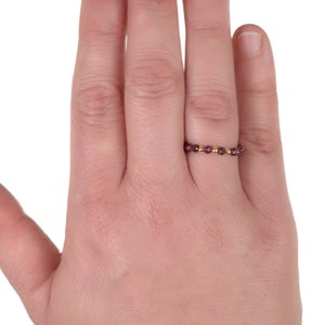 May include: A delicate gold ring with a band of small, dark purple gemstones.
