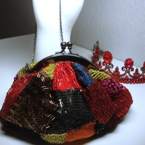 May include: A small, beaded purse with a silver chain and clasp. The purse is made of red, black, brown, and gold beads and sequins.