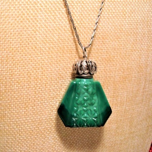 May include: A green glass bottle pendant necklace with a silver filigree stopper. The bottle has a geometric shape and a detailed design.