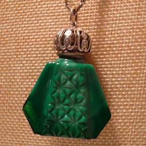 May include: A green glass bottle pendant with a silver filigree top. The bottle has a faceted design and is attached to a silver chain.