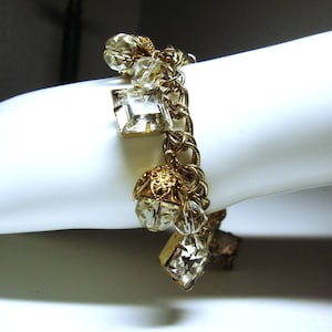 May include: A gold chain bracelet with clear crystal charms. The bracelet features a variety of crystal shapes, including round, square, and teardrop.