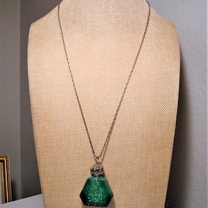May include: A silver chain necklace with a green glass bottle pendant. The bottle has a detailed silver top and a faceted design.