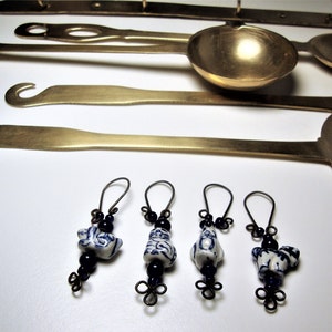 May include: Four pairs of blue and white ceramic bead earrings with black beads hanging from a black wire loop.