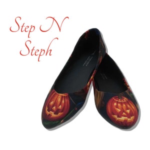 Könnte beinhalten: Ein Paar schwarze Ballerinas mit einem Halloween-Motiv, das orangefarbene Kürbisgesichter auf einem dunklen Hintergrund zeigt.