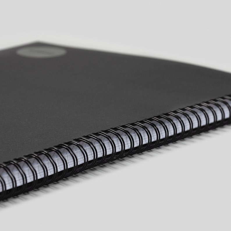 May include: A black spiral bound notebook with a black cover.