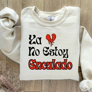 May include: A cream-colored sweatshirt with the text "Ya No Estoy Enculado" in black and red lettering. A broken red heart with dripping red paint is next to the text.