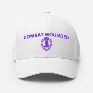 Könnte beinhalten: Eine weiße Baseballkappe mit dem violett gestickten Text COMBAT WOUNDED über einem violetten herzförmigen Emblem, das die Silhouette eines Personenprofils enthält. Die Kappe hat eine strukturierte Krone, einen gebogenen Schirm und einen Knopf.