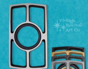 May include: A silver metal frame with a black center ring and four black rectangular openings. The frame is on a blue background. Vintage Revival Art Co. is printed in white text on the background.
