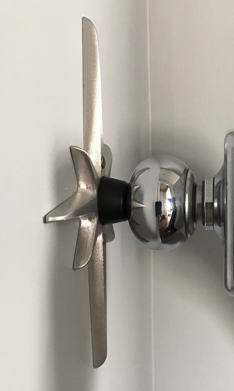 May include: A silver metal wall mount with a star-shaped base and a round ball at the end. The mount is attached to a white wall.