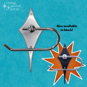 May include: A chrome toilet paper holder with a diamond-shaped backplate. The backplate is available in silver or black.  "Also available in black!" is written in black text on a white background.