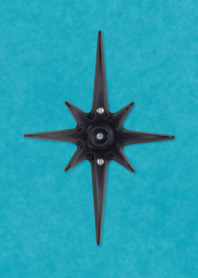 May include: A black metal star-shaped door knocker with a circular center and six points. The knocker is mounted on a blue wall.