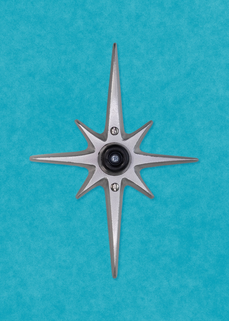 May include: A silver star-shaped door knocker with a black peephole in the center, mounted on a blue wall.