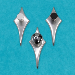 May include: Three diamond-shaped cabinet knobs with different colored centers. The knobs are silver with a black, white, and chrome center.