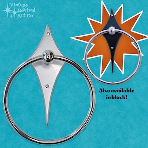 May include: A chrome towel ring with a diamond-shaped backplate. The backplate is silver with a black version shown in the background. The text "Also available in black!" is visible in the image.