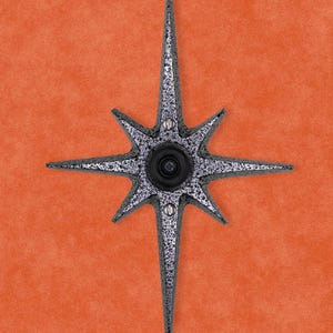 May include: A silver star-shaped door knocker with a round peephole in the center.
