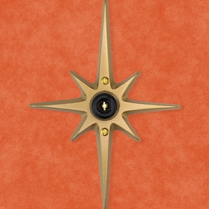 May include: A gold-toned starburst-shaped doorbell button with a black center and a small keyhole.