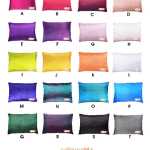 Könnte beinhalten: Eine Sammlung von 16 Seidenkissenbezügen in verschiedenen Farben, darunter Pink, Lila, Gelb, Orange, Blau, Grün und Grau. Die Kissenbezüge sind in vier Reihen zu vier angeordnet, wobei jeder Kissenbezug mit einem Buchstaben von A bis T gekennzeichnet ist.