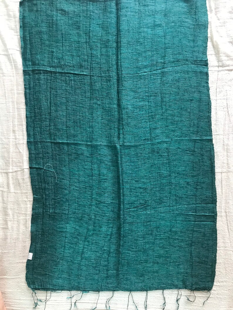 May include: A teal green silk scarf with a textured woven pattern and fringed edges.