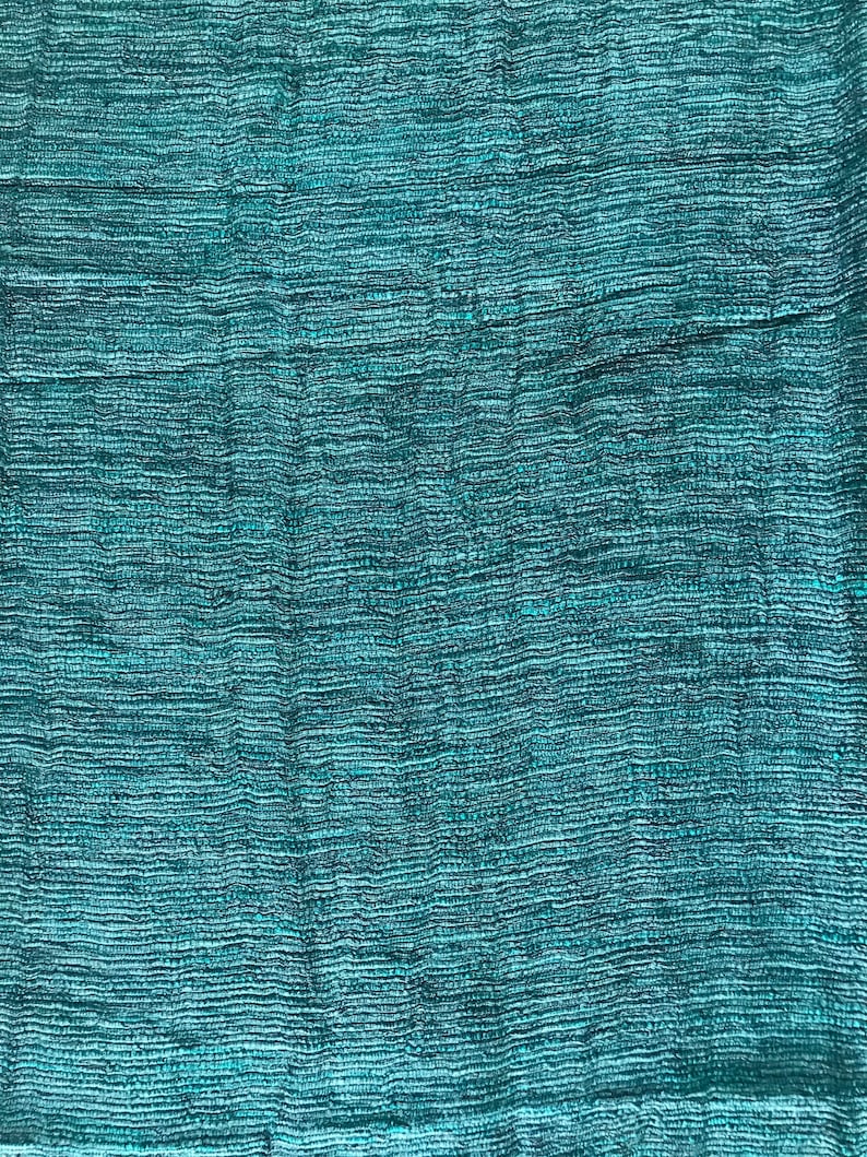 May include: A close-up of a teal blue woven fabric with a textured surface.