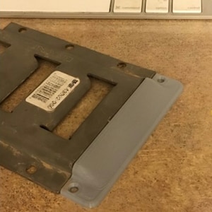 May include: A gray metal plate with four rectangular cutouts and a gray plastic cover with a screw hole. The plate has a barcode label with the number 43002-050.