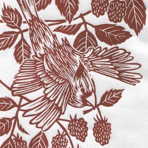 May include: A brown linocut print of a bird perched on a branch with red berries. The bird is facing left and has its wings spread out. The berries are clustered together on the branch.