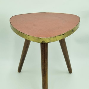 Midcentury tripod plant stand, red colored top, brass frame, three wooden legs, triangular coffee table formica table, 1950s Germany