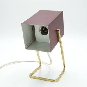 May include: A vintage table lamp with a burgundy square shade and a brass base. The lamp has a white cord and a standard light bulb socket.