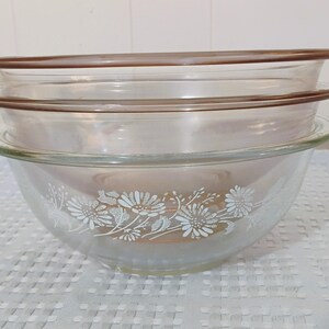 May include: Set of three glass mixing bowls with a brown rim and white floral design.