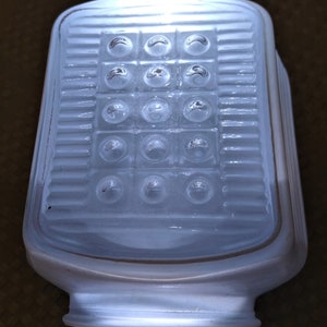 May include: White frosted glass ceiling light fixture with a rectangular shape and a grid of round, raised, clear glass circles.