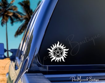May include: White vinyl decal of a five-pointed star inside a sunburst design. The decal is on the back window of a black truck. The text "Pixie Mermaid Boutique" is visible in the lower right corner of the image.