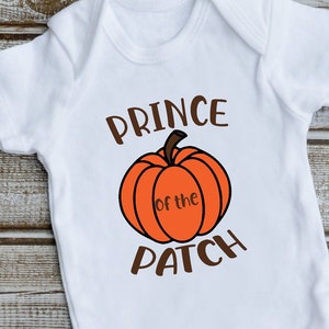 May include: White baby onesie with brown text that reads "Prince of the Patch" and a cartoon orange pumpkin.