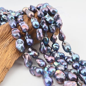 Pode incluir: Um fio de pérolas barrocas de forma irregular com um brilho metálico iridescente em tons de azul escuro e roxo. As pérolas estão enfiadas, exibindo texturas orgânicas variadas e superfícies refletoras com reflexos esverdeados.