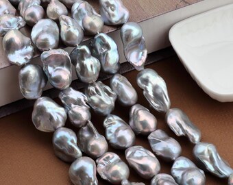 May include: A close-up of a collection of irregularly shaped, iridescent grey pearls. The pearls have a lustrous sheen and vary in size and form. The image highlights the unique textures and colours of the pearls. The pearls are strung together.