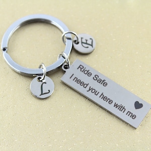 以下が含まれることがあります： シルバーのキーホルダーに、"Ride Safe I need you here with me"とハートが書かれたシルバーのチャームが付いています。キーホルダーには、"L"の文字が刻まれたシルバーのチャームが2つ付いています。