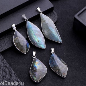 May include: Five silver pendant charms with iridescent blue and gray labradorite stones. The stones are shaped like teardrops with a pointed tip and a rounded base.