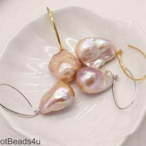 May include: A set of four baroque pearl earrings with gold and silver hoops. The pearls are a soft pink color with iridescent highlights.