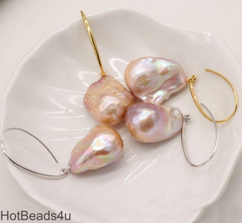 May include: A set of four baroque pearl earrings with gold and silver hoops. The pearls are a soft pink color with iridescent highlights.