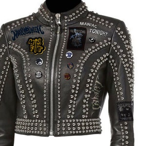 May include: Black leather jacket with silver studs and patches. The jacket has a zipper closure and multiple patches with text and graphics, including "Halloween" and "Maniac Tonight."