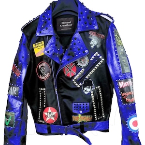 May include: Black leather jacket with blue panels, studded embellishments, and patches. Includes text and graphics such as "Royal Leather" and "The Clash". Features a belt and zip closure.