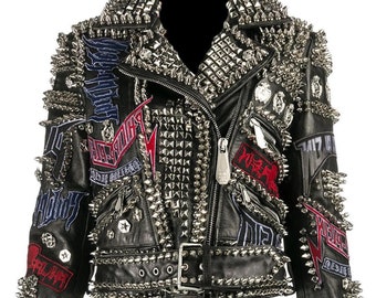 Könnte beinhalten: Schwarze Lederjacke mit silbernen Metallnieten und -spitzen. Die Jacke hat einen Reißverschluss, einen Gürtel und aufgestickte Aufnäher. Kragen und Schultern sind stark mit Nieten verziert.