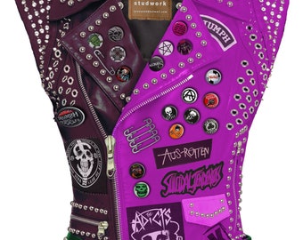 Può includere: Un giubbotto di pelle viola e bordeaux con borchie argentate e una cintura con borchie verdi. Il giubbotto ha varie toppe di band, tra cui "Triumph", "Aus-Rotten", "The Addicts" e "Studded Leather".