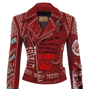 Op de afbeelding: Een rood leren jack met zilveren studs en een riem. Het jack heeft verschillende patches met tekst en afbeeldingen, waaronder "Punk is not just a sound. The music punk is a lifestyle. Be Afraid. Be Very Afraid." en "Eat Rich".